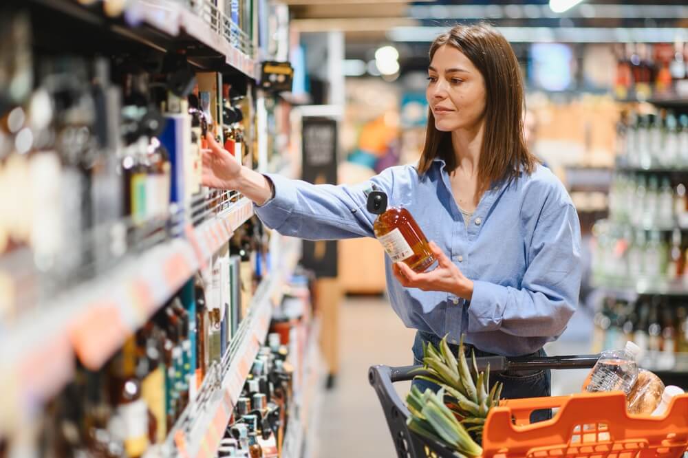Woman,Making,A,Purchasing,Decision,,Holding,A,Bottle,And,Reaching